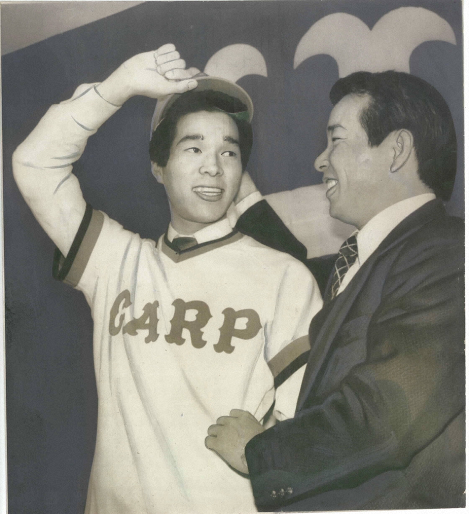 1981年12月2日の入団発表で、赤ヘルのユニホームを着て「新人王を狙いたい」とキッパリ宣言した津田投手（左）。古葉竹識監督の激励にさわやかな笑顔をみせる