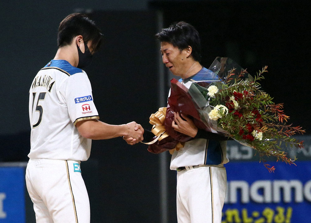 引退試合で、上沢（左）から花束を渡され感極まる浦野