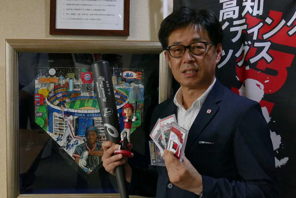 トレーディングカードの熱心なコレクターでもある龍馬学園の佐竹新市理事長は大谷のカードとバットを手に笑顔