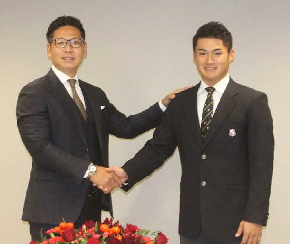 仮契約を終え、担当の松本スカウト（左）と笑顔で握手する広島・ドラフト4位の田村