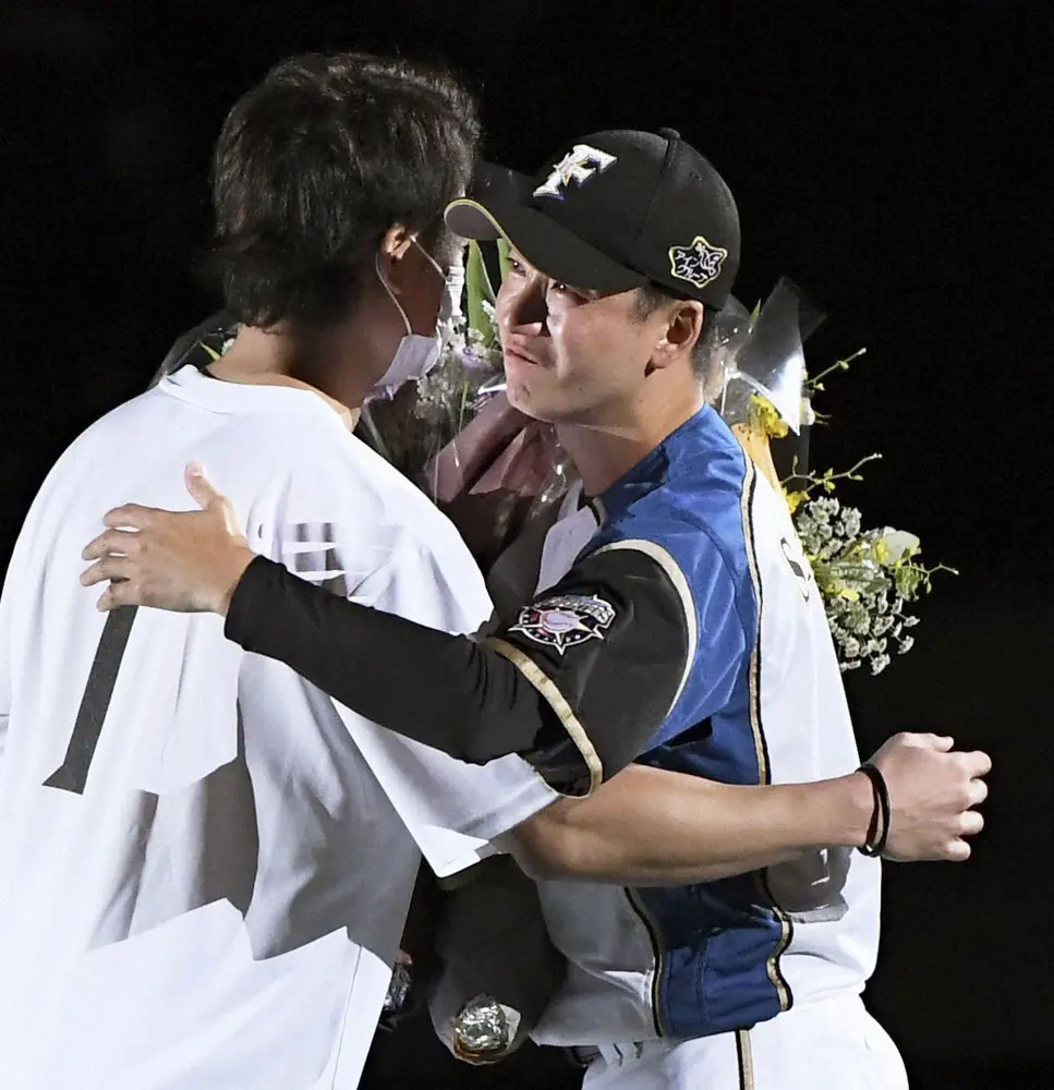 引退セレモニーで西川から花束を贈られ、抱き合う日本ハムの斎藤佑樹投手