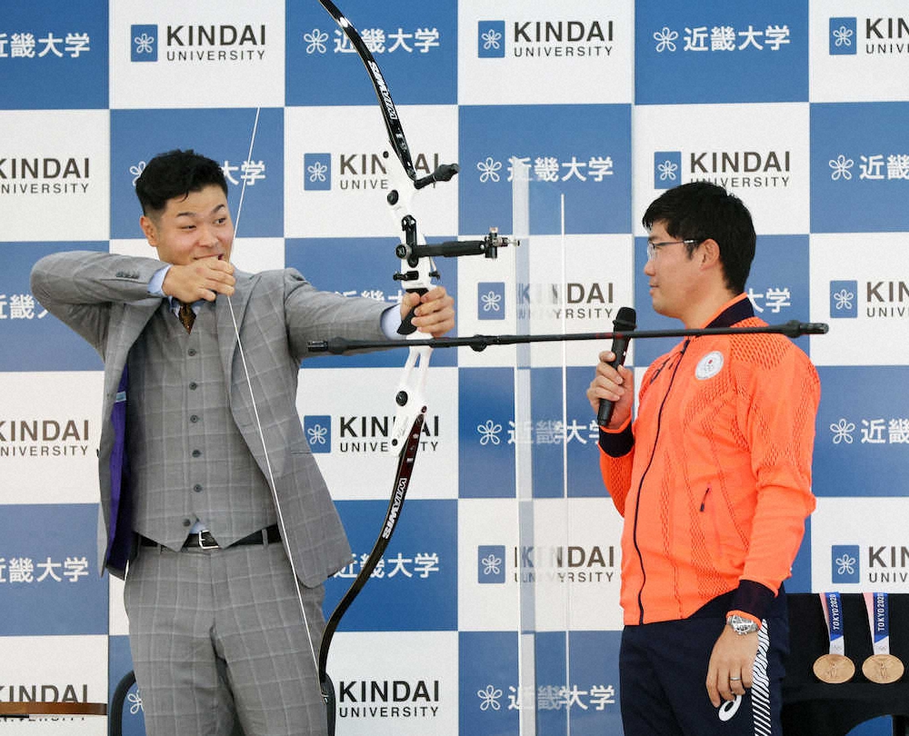 母校・近大で東京五輪アーチェリー銅メダリストの古川高晴（右）とトークショーを行い、壇上で弓を引く佐藤輝（撮影・北條 貴史） ― スポニチ ...