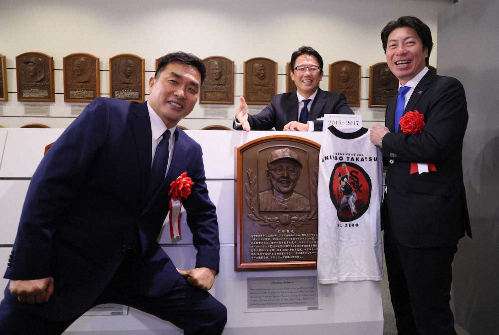 古田氏（中央）のレリーフを挟み記念撮影する山本昌氏（左）と大リーグ時代のTシャツをもつ高津監督