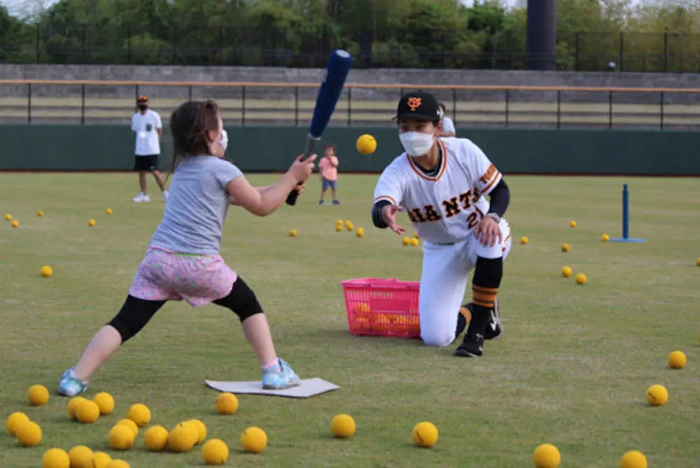 ＜読売ジャイアンツ女子チーム　ベースボールキャラバン＞子どもに柔らかいボールをトスしてバットの振り方を教える金満選手（提供写真）