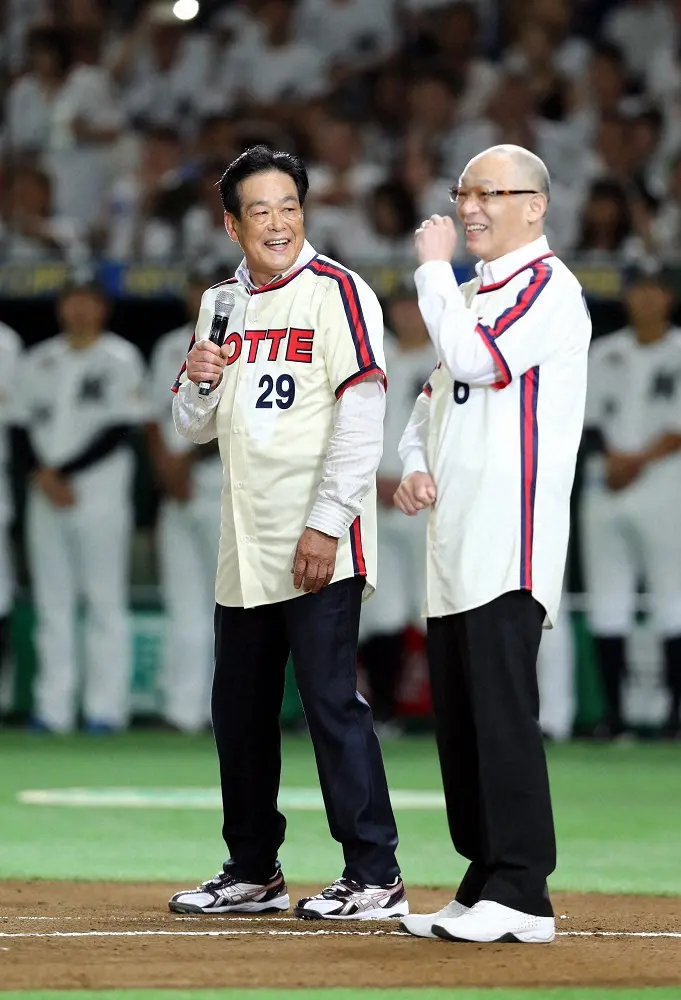 マサカリVS神主打法。試合前セレモニーでスピーチする笑顔の村田氏（左）と落合氏は、始球式で対決