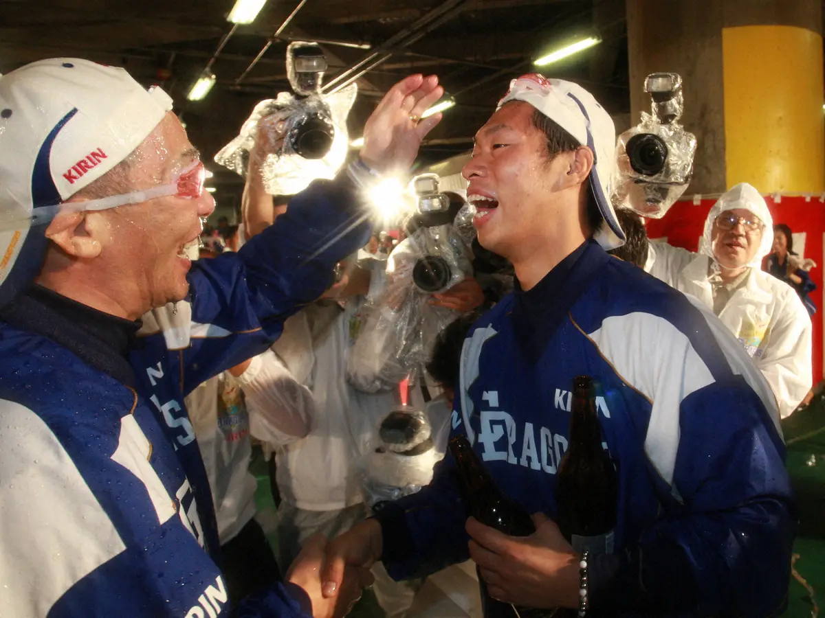 【画像・写真】日本一のビールかけの際、8回パーフェクト投球をした中日先発の山井（右）を労い、ガッチリ握手する落合監督
