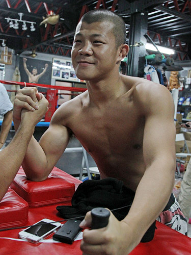 腕相撲マシーンで鍛えられた肉体をアピールする亀田興毅