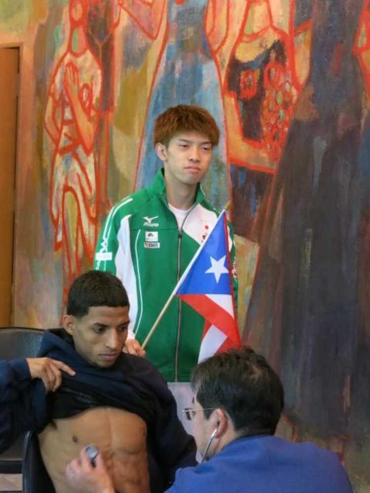 プエルトリコの旗を持ち、アコスタの検診を見守る田中