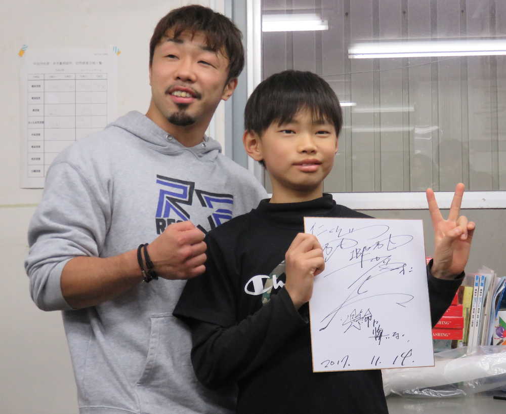 ボクシングジムに通う佐藤仁君（右）は八重樫東からサイン色紙をもらってピースサイン