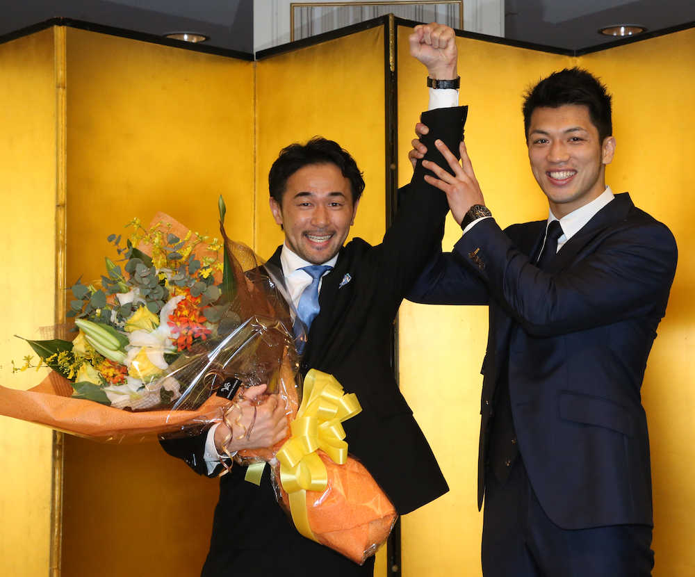 引退会見で村田（左）から花束が贈られ、「神の左」を掲げられる山中