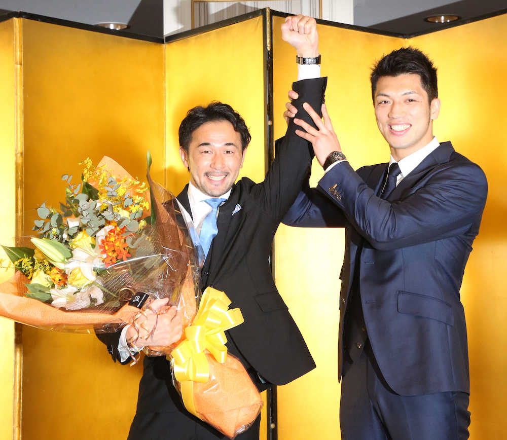 村田（左）から花束が贈られ、「神の左」を掲げられる山中