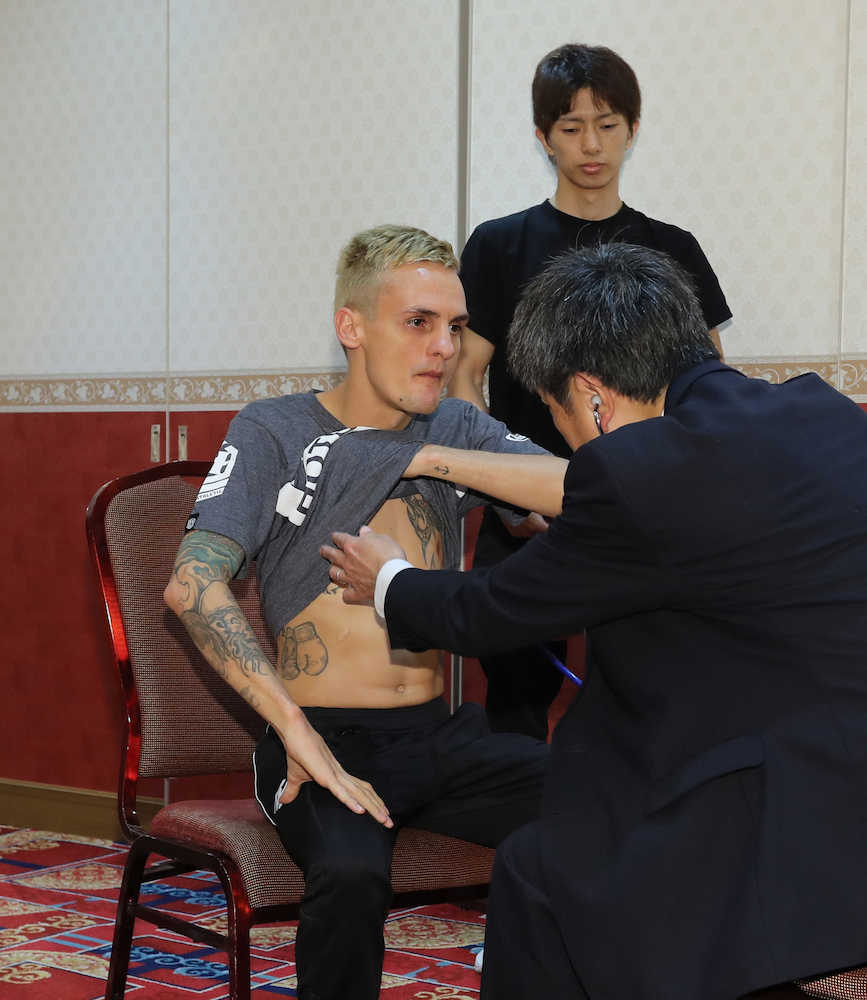予備検診を受けるブドラー（左）のタトゥー入りの体に目をやる統一世界ライトフライ級王者・田口（上）