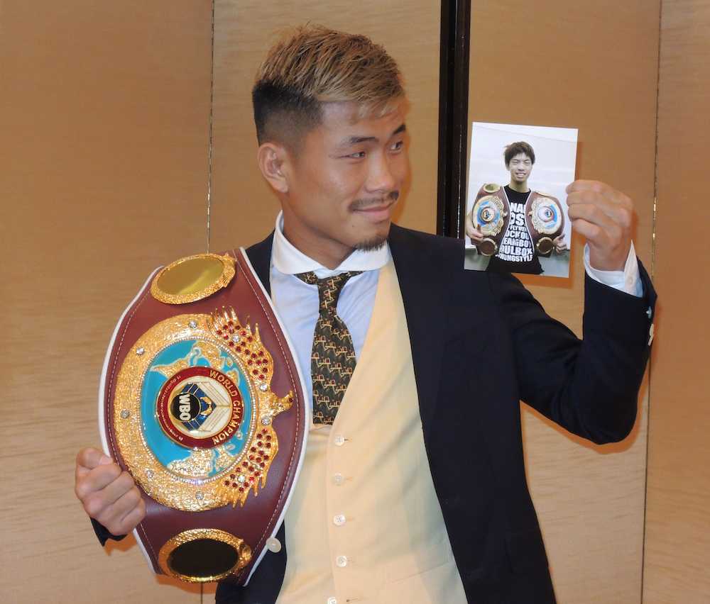 チャンピオンベルトと田中恒成の写真を手に自信の笑みを浮かべる木村翔