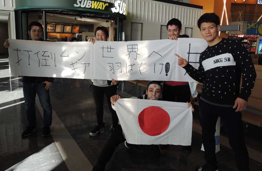 出発を前にワールドスポーツジムの寮生たちが手作りした横断幕の前で笑顔を見せる井上岳（右）