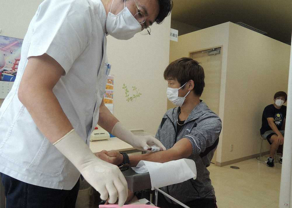 横浜市内のクリニックで抗体検査を受ける清水聡（中央）。右は順番を待つ井上浩樹