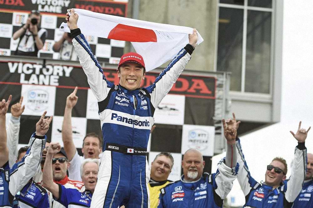 インディカー・シリーズで今季初優勝を果たし、日の丸を掲げて喜ぶ佐藤琢磨（IndyCar提供・AP）