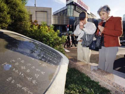 永井さんのヒット曲「有楽町で逢いましょう」の歌碑の前で手を合わせる夫婦＝有楽町