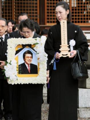 遠藤実さんの葬儀で位牌（いはい）を手にする長女由美子さん（右）