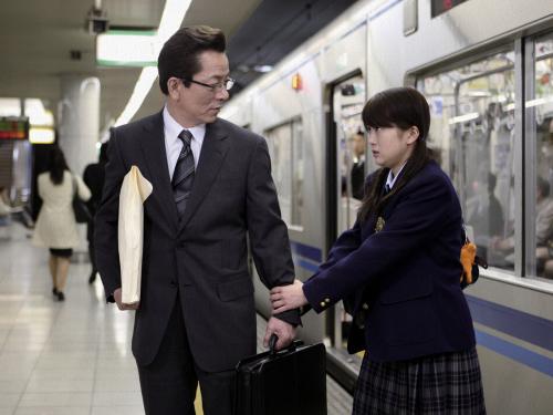 ドラマ「誰かが嘘をついている」の一場面。水谷豊（左）演じるサラリーマンは電車を降りると女子高生に腕をつかまれた