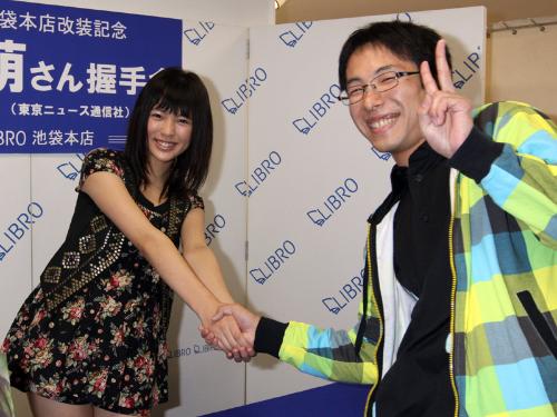 荒井萌（左）は写真集発売記念イベントに１番のりしたファンと握手を交わす