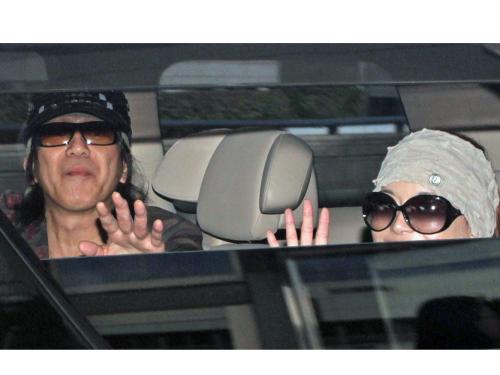 羽田空港から迎えの車に乗り込んだ玉置浩二（左）と青田典子は報道陣に向かって笑顔で手を振る