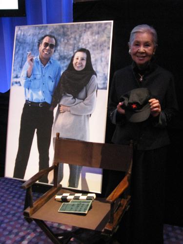 「和田勉さんお別れ会」の開会前に会見した妻のワダエミ。勉さん愛用のディレクターズチェアの前で愛用のキャップを手にする