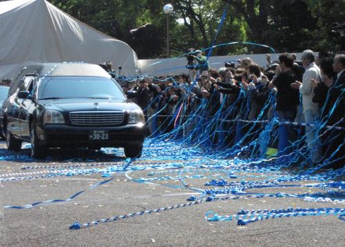 田中好子さんの棺が納められた霊きゅう車の周辺にはファンが投げた青色のテープがじゅうたんのように広がる