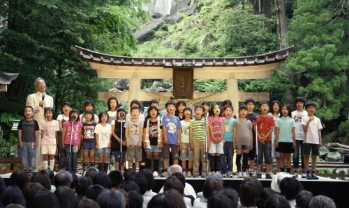 子どもたちと合唱する歌手の谷村新司さん（左奥）