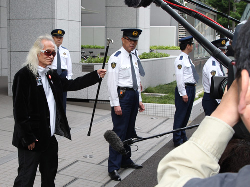釈放された内田裕也は集まった報道陣に向かって杖をかかげる