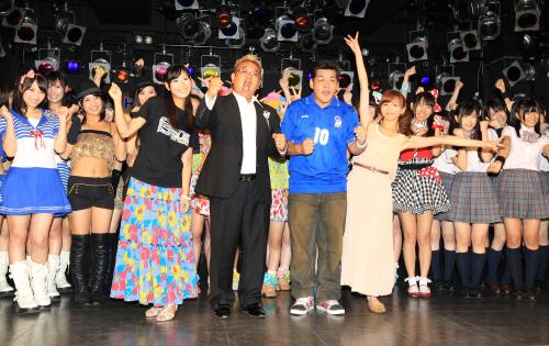 ご当地アイドルたちとポーズをとるお笑いコンビ「サンドウィッチマン」の伊達みきお（前列中央左）と富澤たけし（同右）