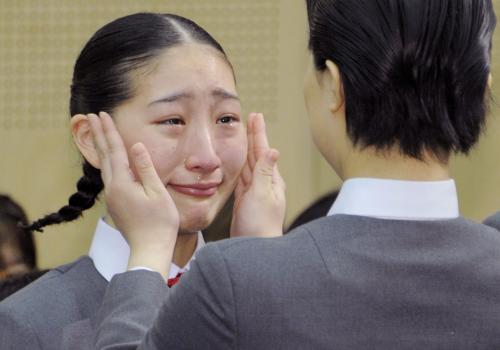 宝塚音楽学校の入学式で、在校生（右）に校章バッジをつけてもらい感極まる新入生