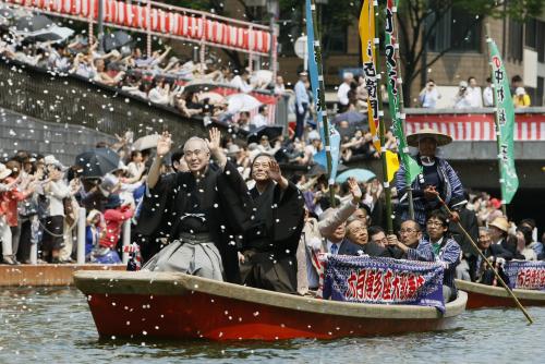 博多座での歌舞伎公演を前に行われた「船乗り込み」で、紙吹雪が舞うなか川岸に詰め掛けたファンに手を振る中村吉右衛門（先頭）ら