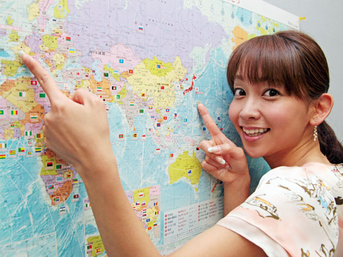 北京に続き、五輪キャスターとして現地からリポートするＴＢＳ出水麻衣アナは、世界地図のイギリスと日本を指さして笑顔