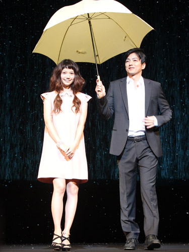 バックに雨と雪を降らせた演出で傘を差しステージに登場する宮崎あおいと大沢たかお