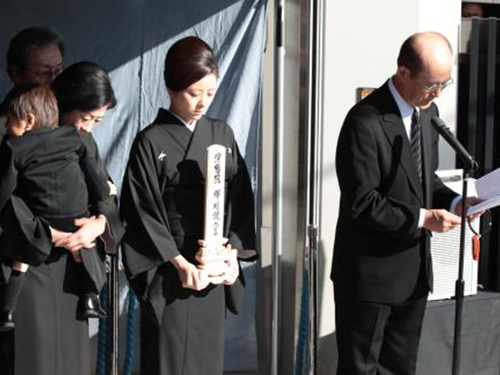 （左から）孫の七緒八くんを抱いた勘三郎夫人の好江さん、勘九郎夫人の愛さん、家族のメッセージを読み上げる野間脩平氏
