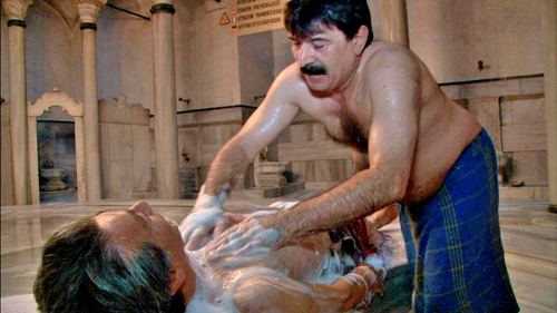 トルコの伝統風呂ハマムで上半身裸の男性に施術を受ける高田純次
