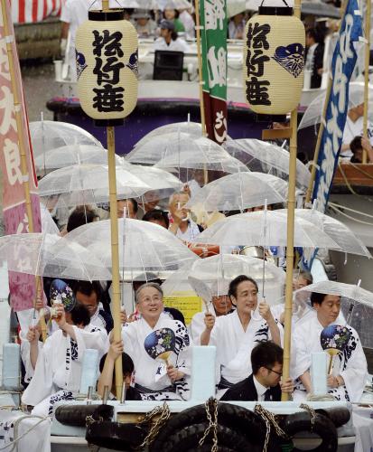 「船乗り込み」で、突然の雨に傘をさす片岡仁左衛門（中央右）ら歌舞伎俳優