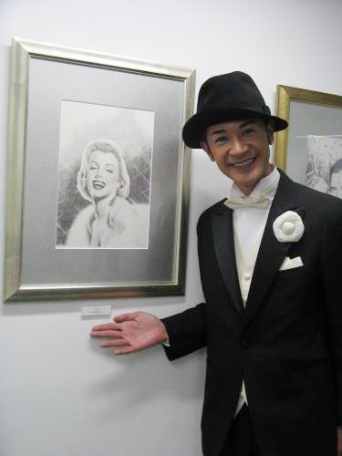 初の個展をスタートさせた山咲トオル。美川憲一が購入したマリリン・モンローの絵画のそばでニッコリ