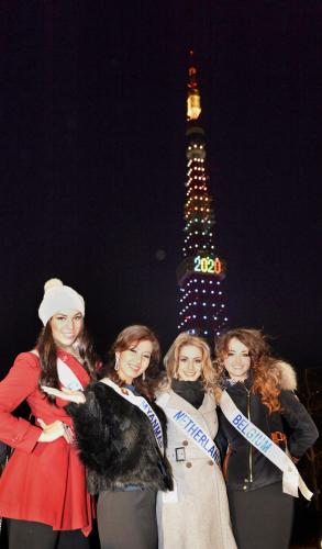 ２０２０年夏季五輪の東京開催を祝い、五輪カラーをイメージしてライトアップされた東京タワーの前で、ポーズをとるミス・インターナショナル世界大会に参加する女性ら