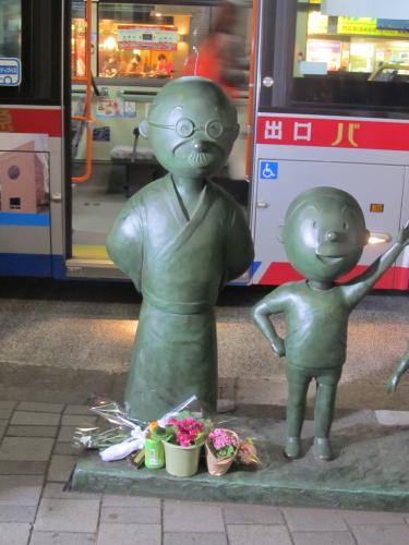 花などが供えられた桜新町駅前に設置された波平の銅像