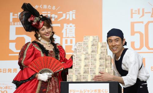 ダミーの札束と笑顔の米倉涼子（左）と原田泰造
