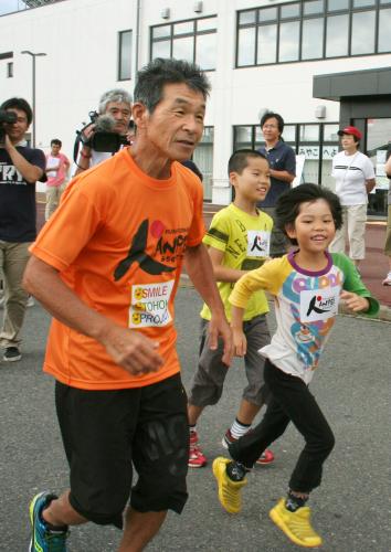 震災から３年５カ月、被災地を縦走するマラソンの出発を前に、小学生とジョギングする間寛平