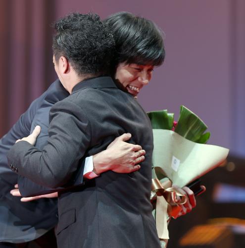 石原裕次郎新人賞を受賞した東出昌大（奥）は、やべきょうすけに花束を手渡されハグする