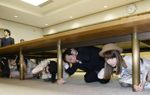 神戸市の「シェイクアウト」訓練で、机の下に避難する柏木由紀（右端）らＡＫＢ48のメンバー。右から２人目は久元喜造市長＝15日午前、神戸市役所