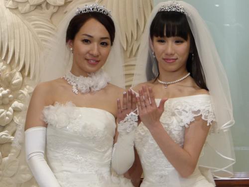 挙式した一ノ瀬文香（左）と杉森茜は互いにウエディングドレスに身を包み結婚指輪を見せる