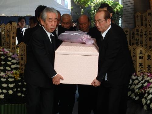 葬儀場から棺を運び出す志村けん（右）