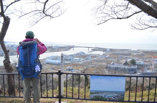 日和山公園から石巻湾を見つめるなすび。ぽつぽつと新しい建物が立っているが、まだ茶褐色の更地が多い。柵には震災前の同所を写した写真がかかっている