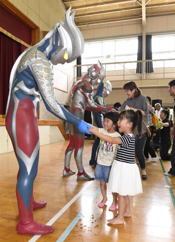 熊本市の小学校を訪れたウルトラマンシリーズのヒーローたちと握手する児童