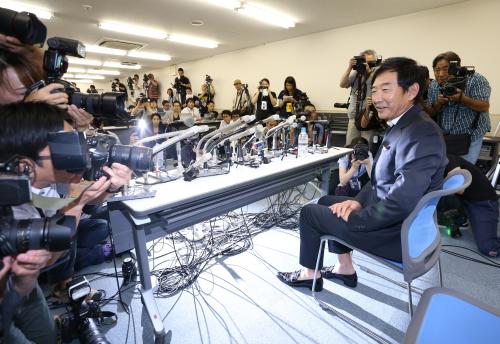 大勢の報道陣の前で意気込みを語る石田純一。カメラのフラッシュが足元を照らす