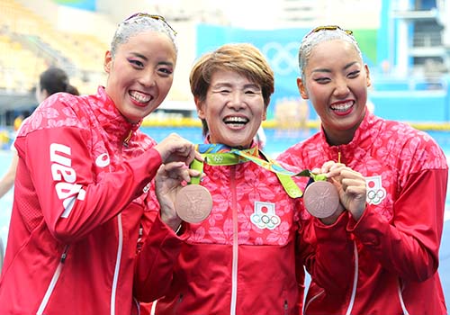 銅メダルをかけられ笑顔を見せる井村監督(中央)